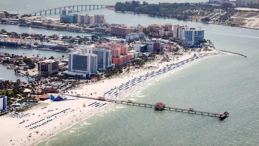 Aerial view of a Gulf beach with a fishing pier, hotels and condo buildings